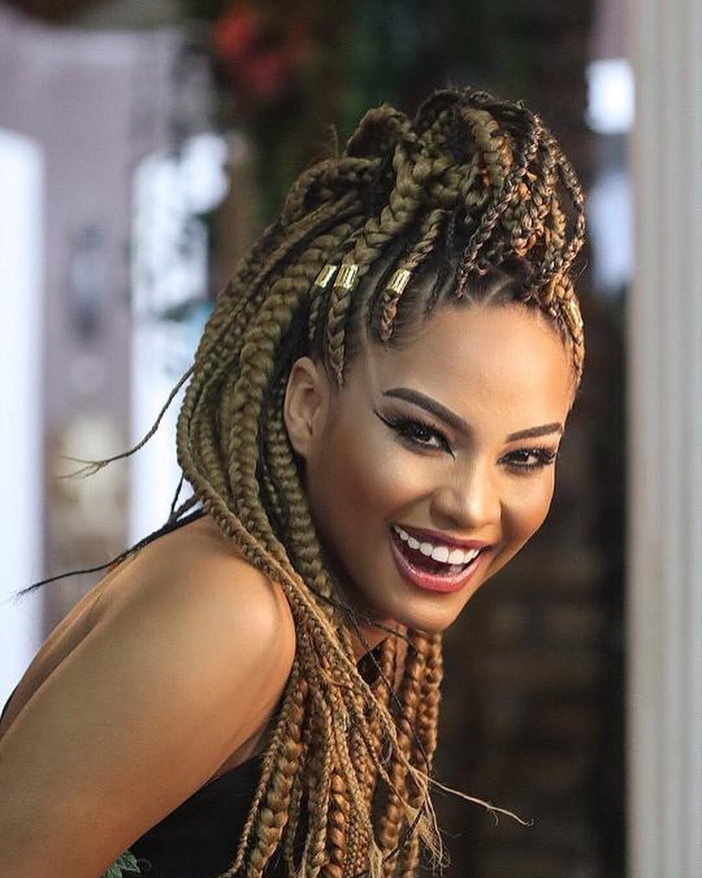 Mulher sorrindo com tranças longas em tons dourados